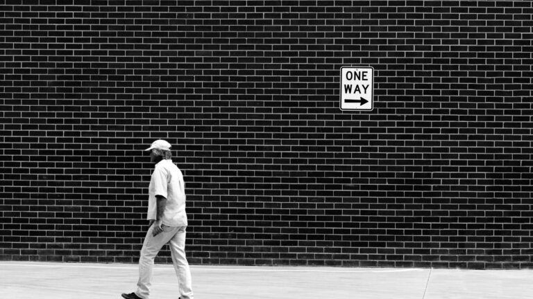 man walking in the opposite direction of a signage