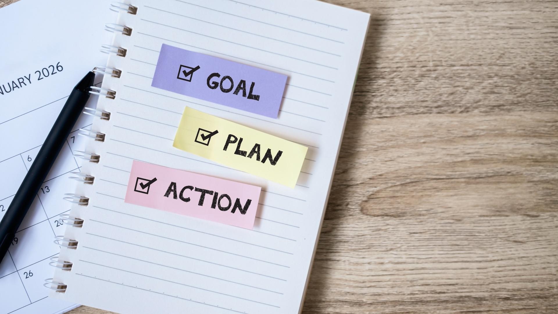 notebook with goal plan and action written on it