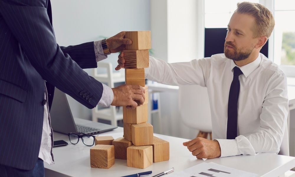 partners building a tower of wooden blocks representing compound