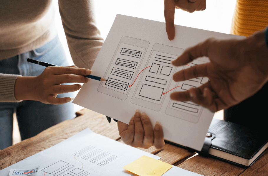 People discussing a flowchart or wireframe on paper