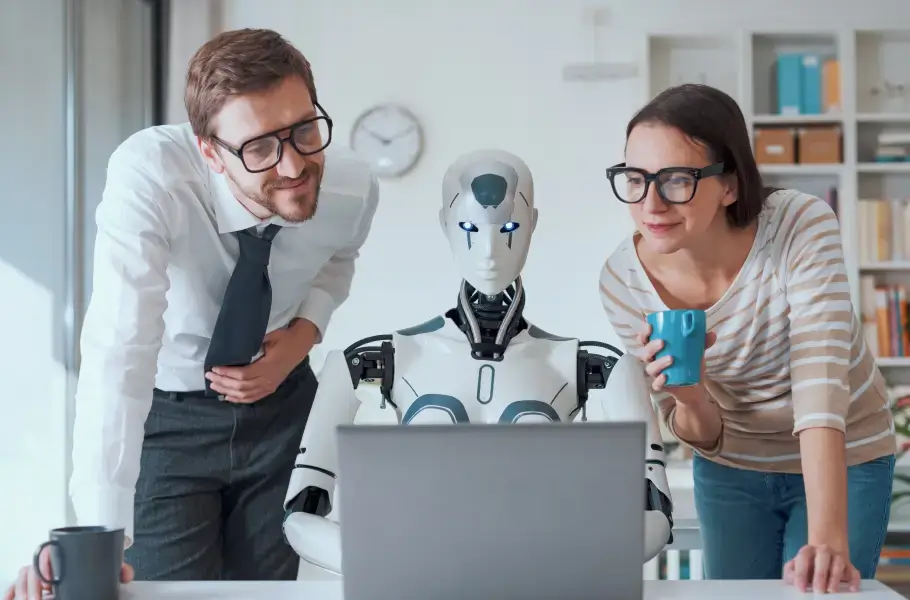 Two people looking at a laptop with a robot between them