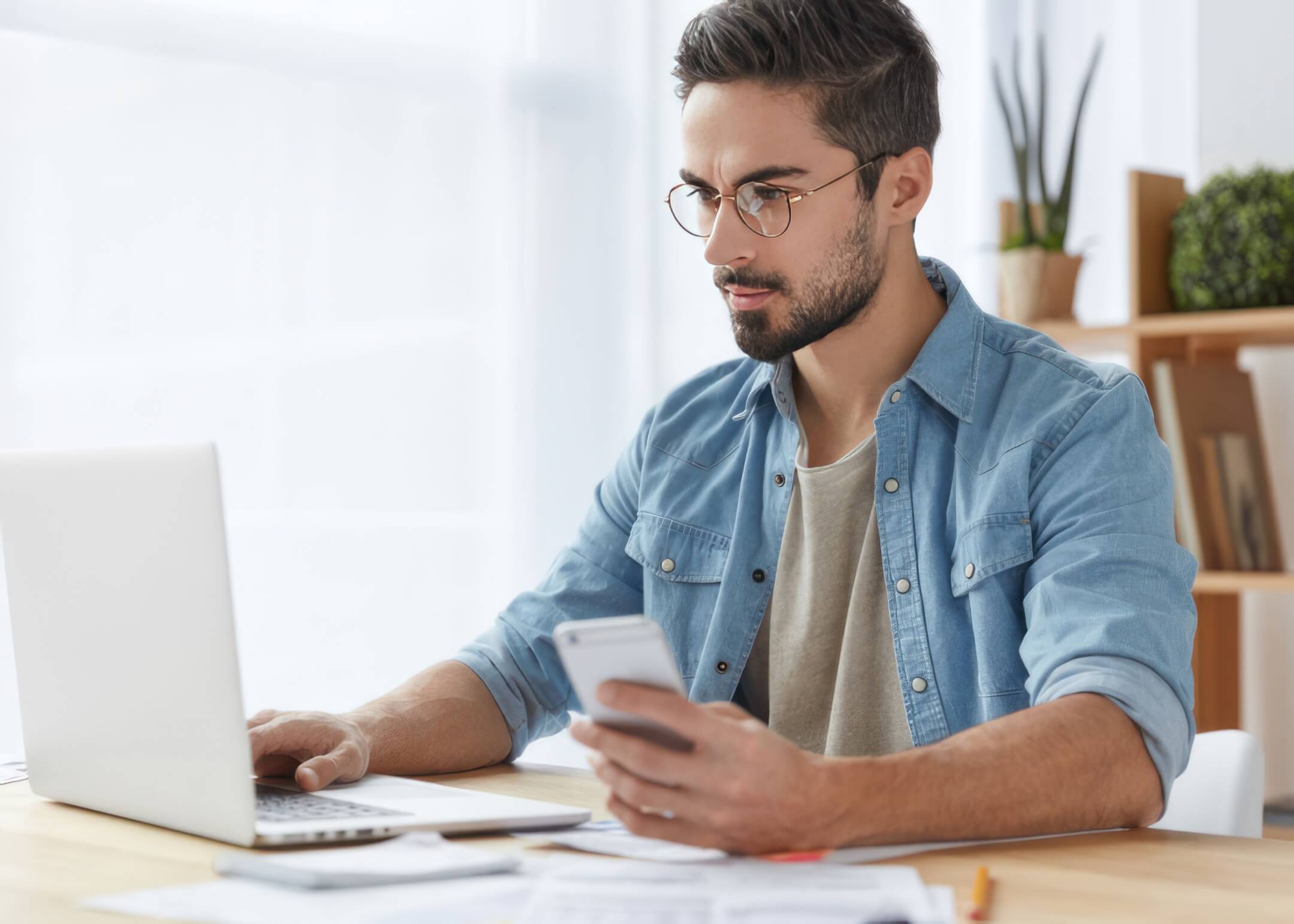 person holding phone looking at computer