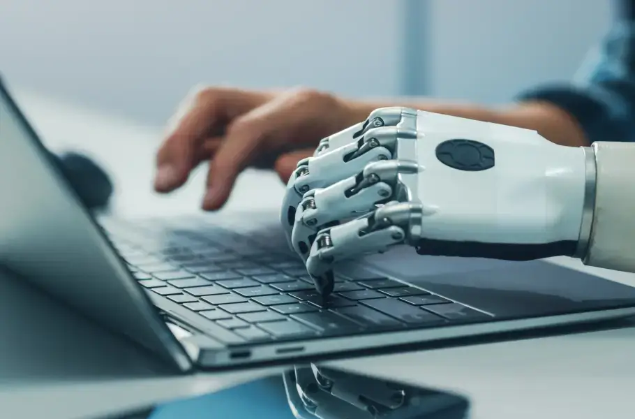 Robotic hand and human hand typing on a laptop keyboard