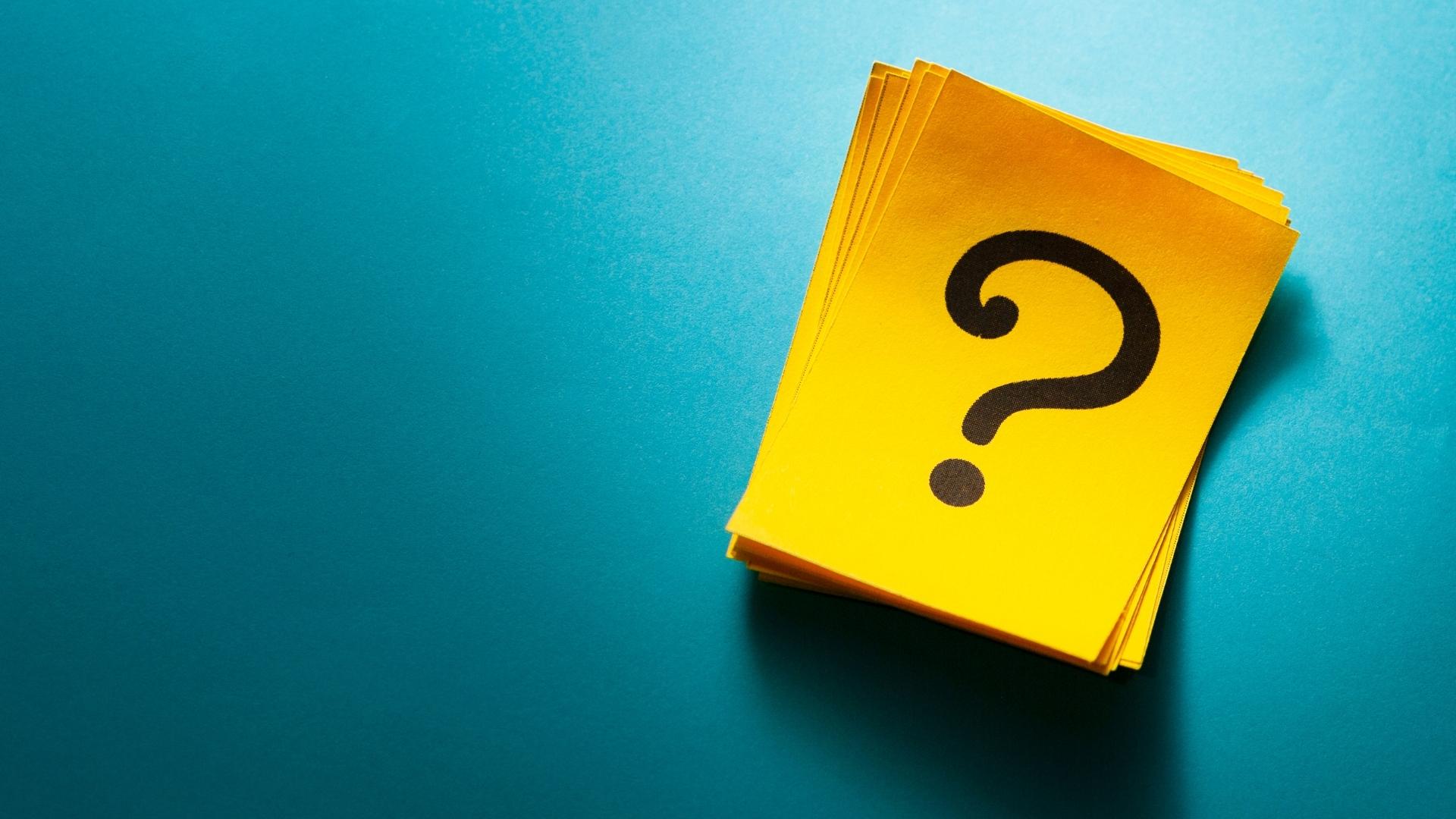 stack of question mark cards on blue green background