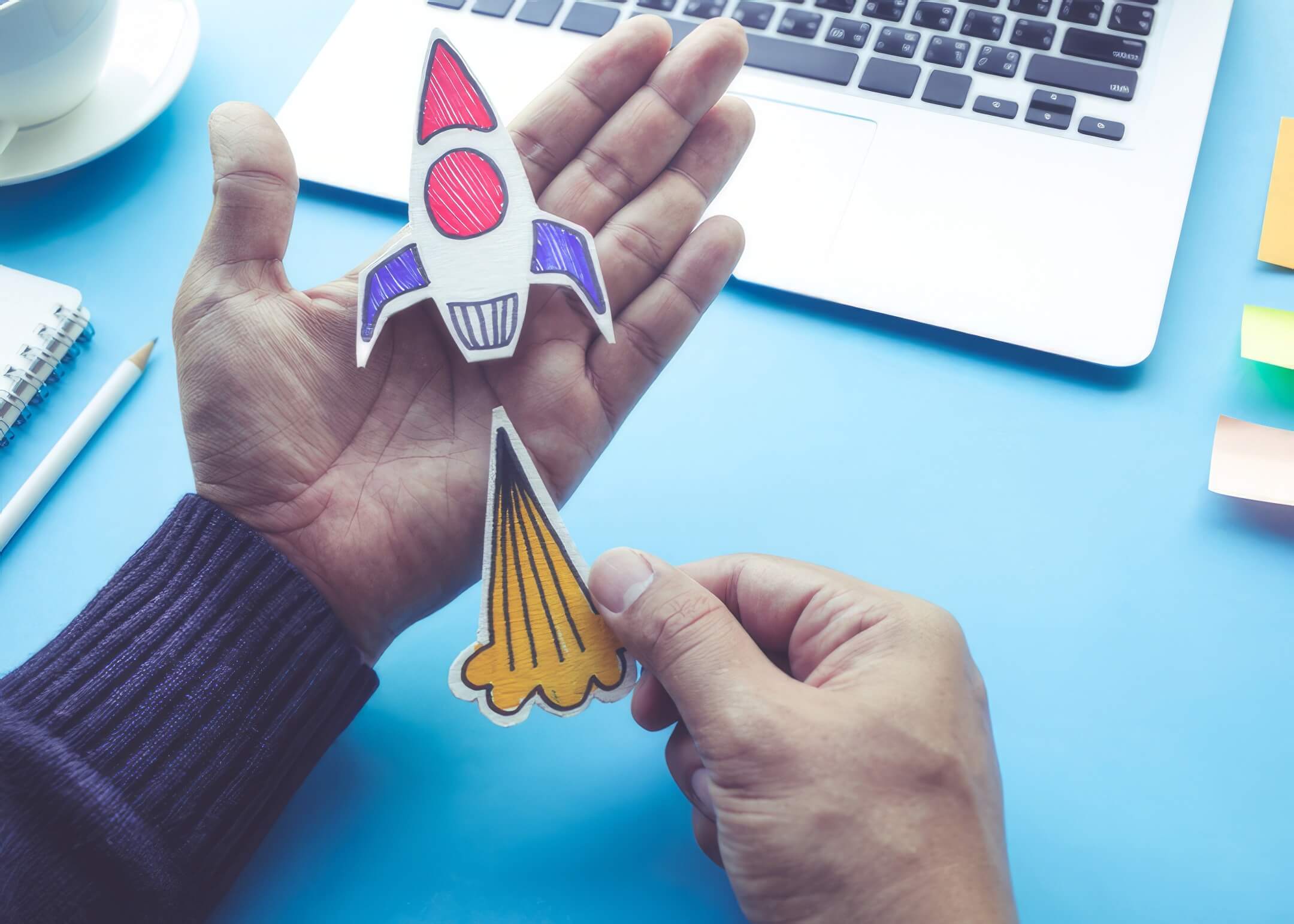 start up concepts with rocket in male hand on desk table