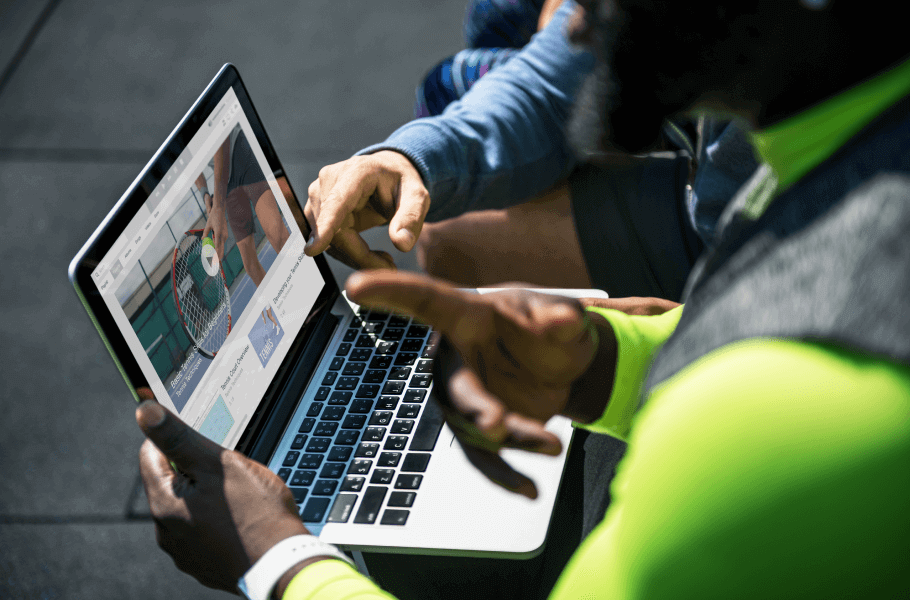 Two people looking at a laptop screen outdoors