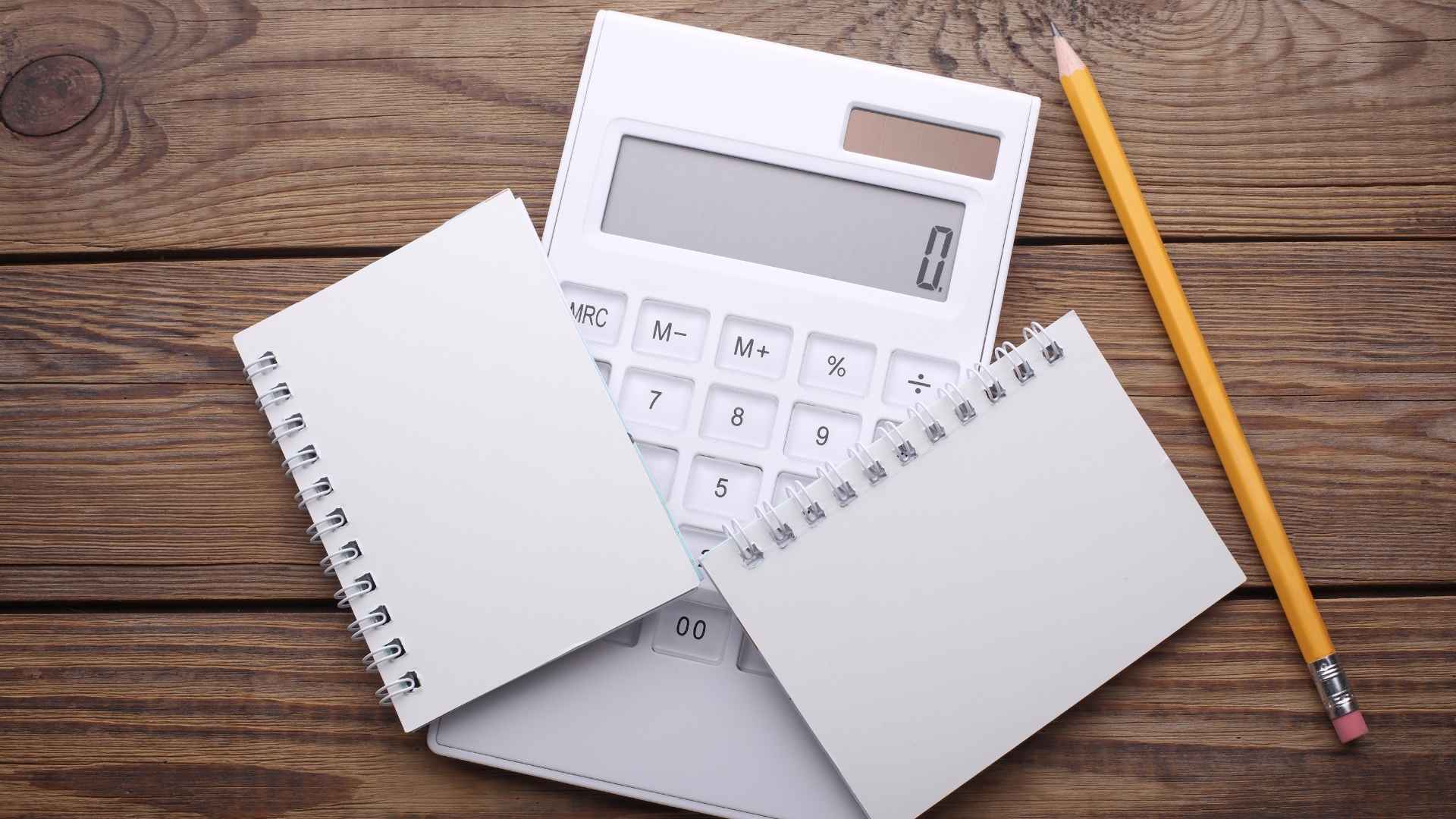 two white blank spiral notebooks with calculator and a pencil