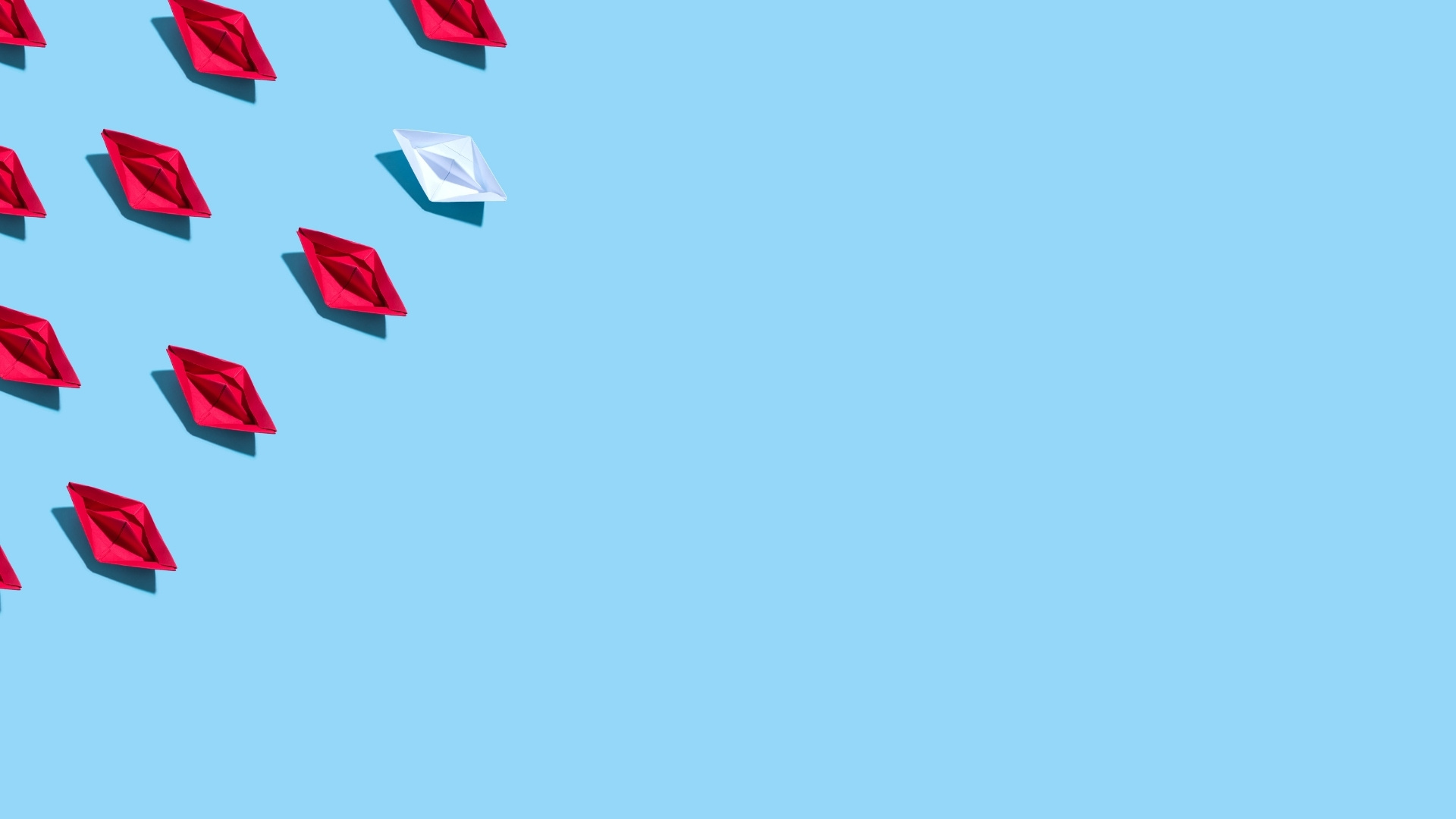 white paper boat surrounded by red ones