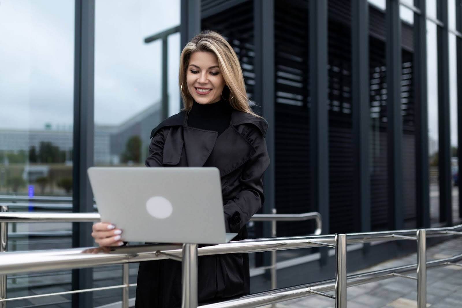 woman checking her laptop while on a bridge