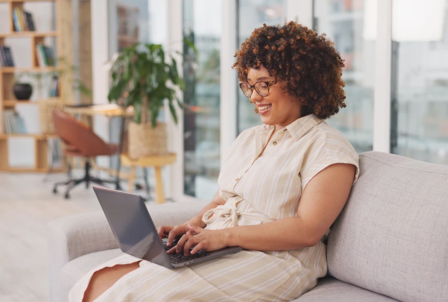 woman sitting on the couch while using her laptop for remote work