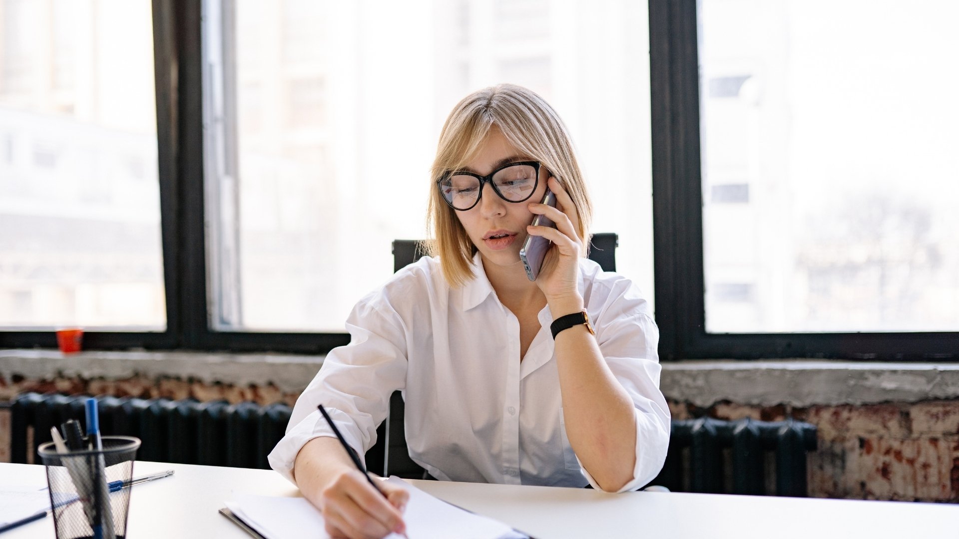 woman taking notes while calling
