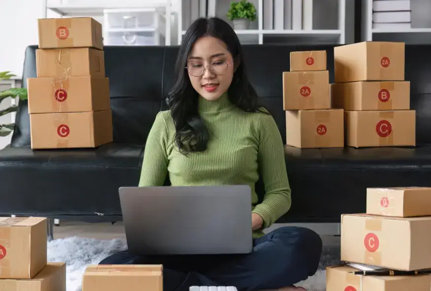 woman using her laptop and lots of boxes in the background