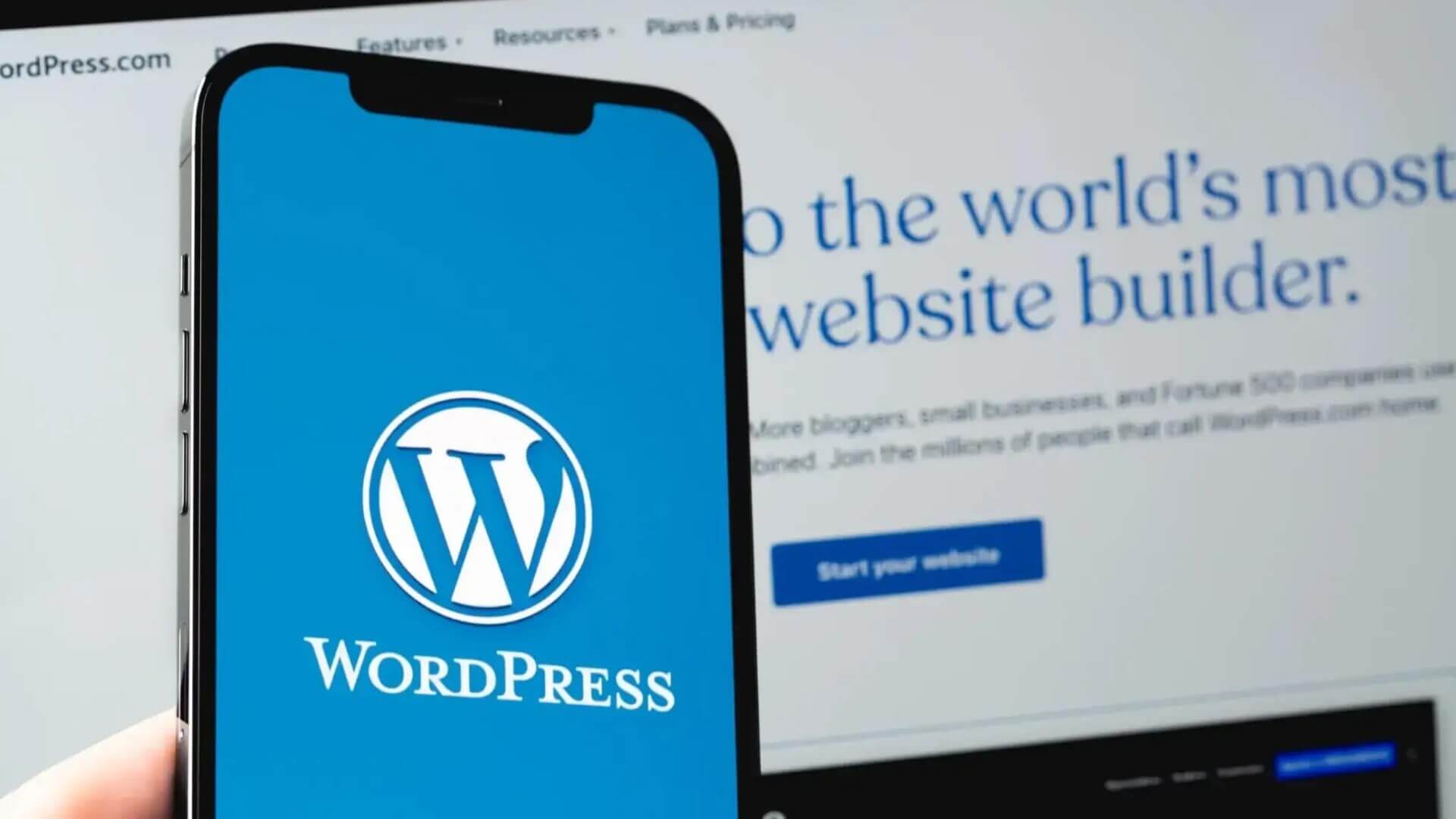 Close-up of a mobile phone and computer monitor displaying the WordPress logo and the homepage of the website builder platform