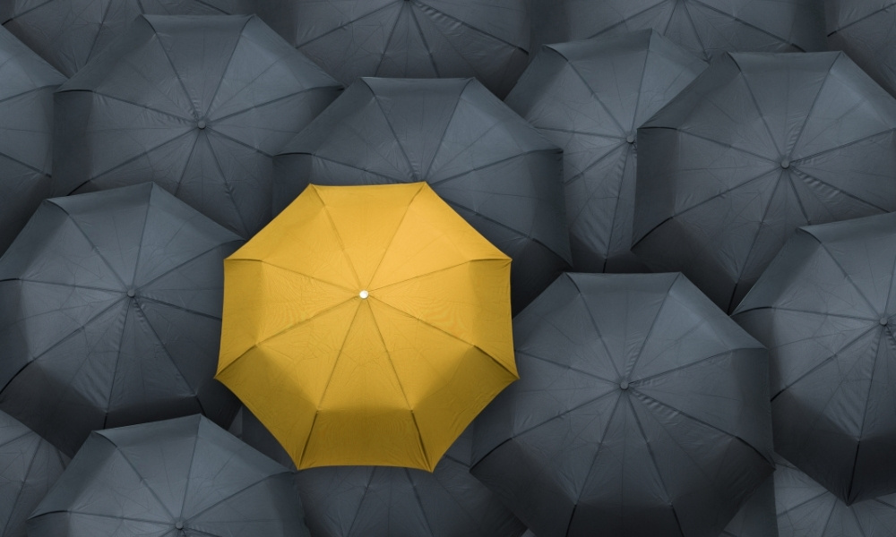 yellow umbrella surrounded by black umbrellas