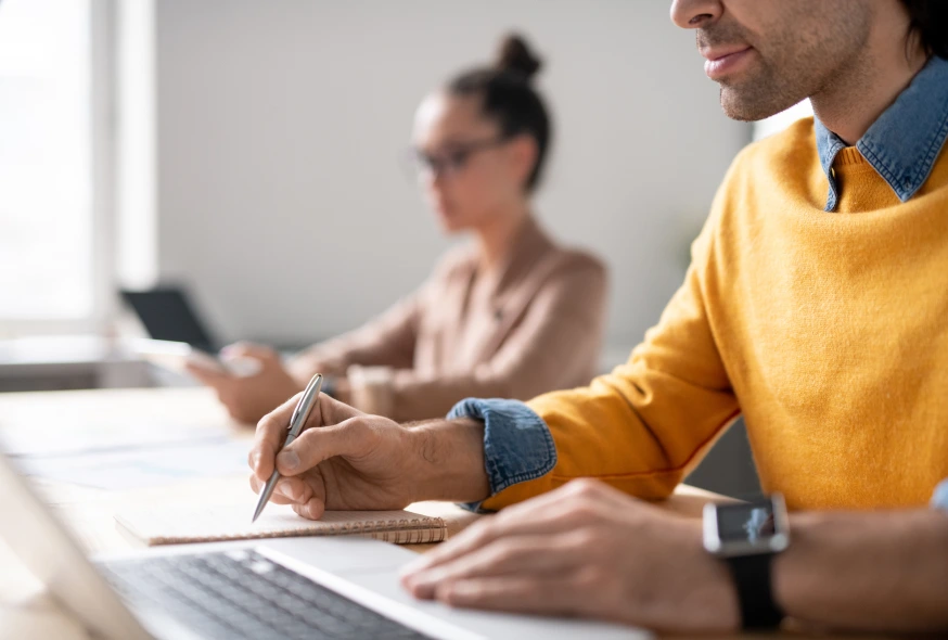 young manager using his laptop while jotting notes